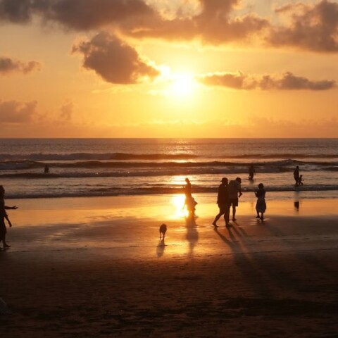 Λουόμενοι σε παραλία με φόντο το ηλιοβασίλεμα