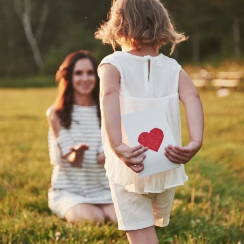 Κοριτσάκι τρέχει προς τη μητέρα του έχοντας κρυμμένη πίσω της μία καρδούλα