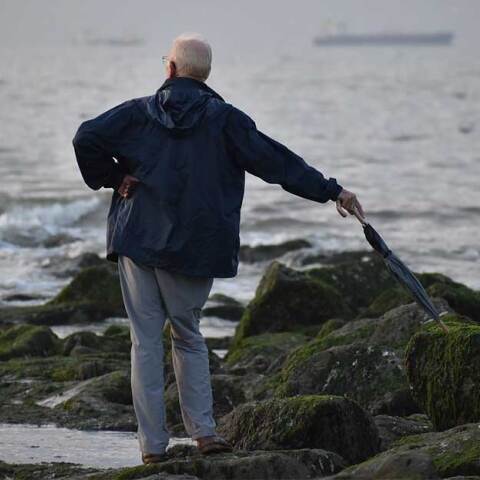 Ηλικιωμένος με ομπρέλα αγναντεύει τη θάλασσα