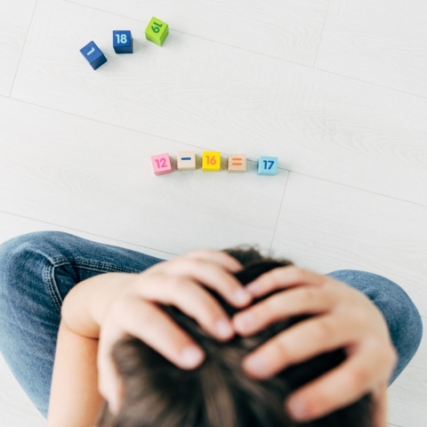 Παιδί που απελπίζεται κάνοντας υπολογισμούς αριθμητικής με τουβλάκια