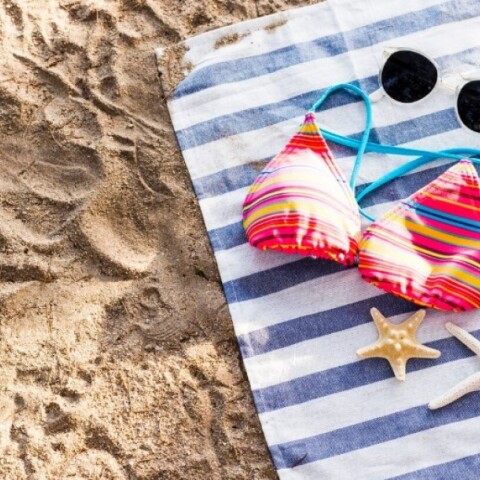 Μαγιό, γυαλιά ηλίου και αστερίες σε πετσέτα θαλάσσης στην άμμο