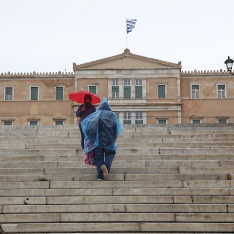 Πολίτες με ομπρέλα και αδιάβροχο μπροστά στη Βουλή