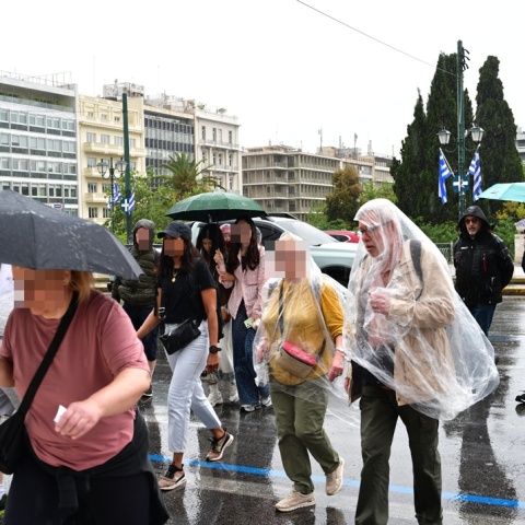 Πολίτες με ομπρέλες ανά χείρας προστατεύονται από τη βροχή