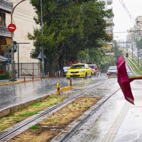 Βροχή και κοπέλες που κλείνουν την ομπρέλα τους σε στάση τραμ