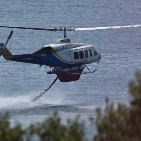 Ελικόπτερο γεμίζει νερό από τη θάλασσα για να το ρίξει σε δασική πυρκαγιά