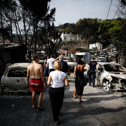 Πολίτες περπατούν ανάμεσα σε καμένα οχήματα την επομένη της τραγωδίας στο Μάτι
