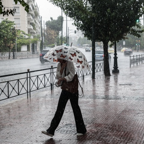 Γυναίκα με ομπρέλα εν μέσω μπουρινιού στο κέντρο της Αθήνας