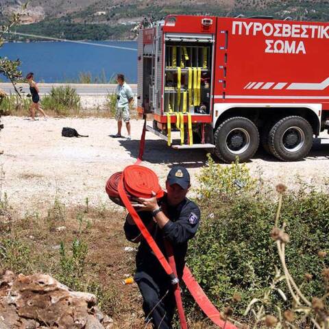 Πυροσβέστης μεταφέρει μάνικα μπροστά από πυροσβεστικό όχημα