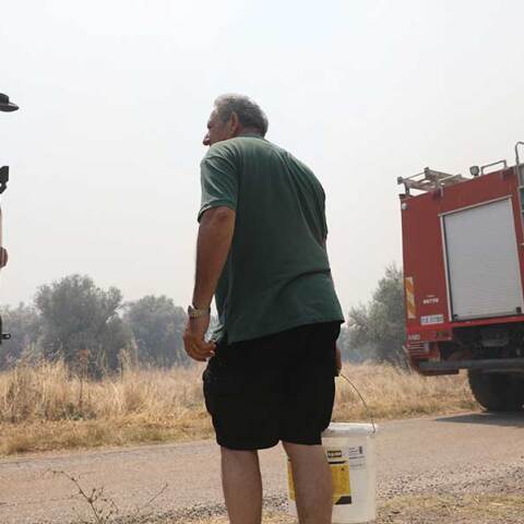 Εθελοντής δίπλα σε πυροσβεστικά οχήματα για να βοηθήσει σε δασική πυρκαγιά