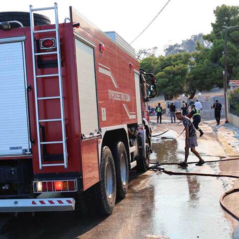 Πυροσβέστες σβήνουν τη φωτιά στη Σαλαμίνα, η οποία απειλεί κατοικίες
