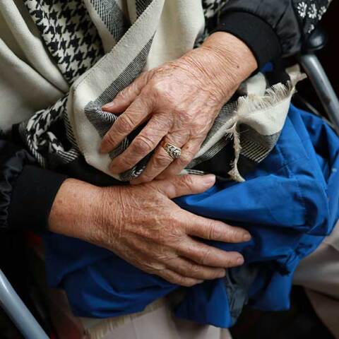Ηλικιωμένη κρατά ρούχα στα χέρια 
