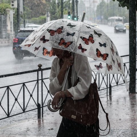 Γυναίκα κρατά ομπρέλα εν μέσω ισχυρής καταιγίδας