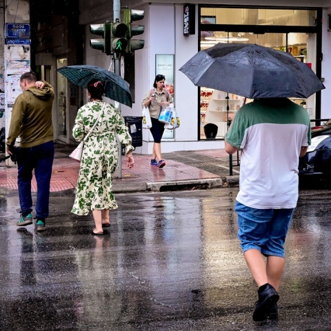 Πολίτες με ομπρέλες εν μέσω βροχής