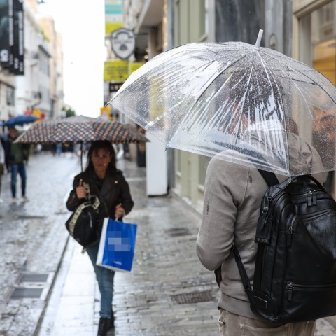 Πολίτες με ομπρέλες σε κεντρικό εμπορικό δρόμο