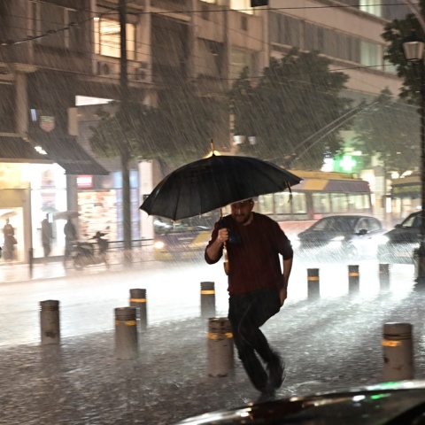 Άνδρας τρέχει κρατώντας ομπρέλα εν μέσω ισχυρής καταιγίδας