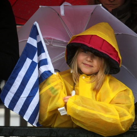 Κοριτσάκι με ομπρέλα και την ελληνική σημαία σε παρέλαση
