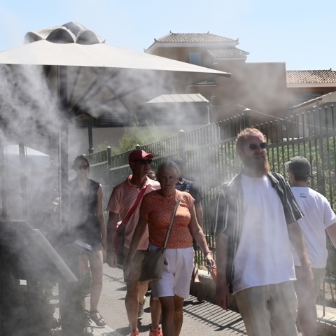 Πολίτες περπατούν υπό υψηλές θερμοκρασίες δίπλα σε σύστημα που βράζει σταγόνες νερού για δροσιά