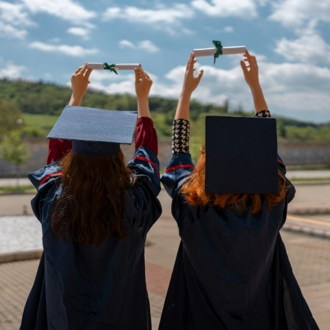 Νεαρές γυναίκες με τίβενο κρατούν στα χέρια τους το πτυχίο τους 