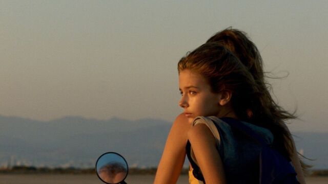 A young girl looking back while riding a motorcycle
