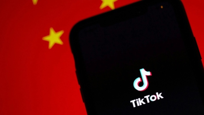 Το logo του TikTok και πίσω μία σημαία της Κίνας