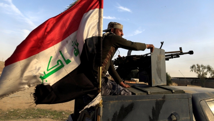 Ιρακινός κάθεται πάνω σε τεθωρακισμένο όχημα με την ιρακινή σημαία
