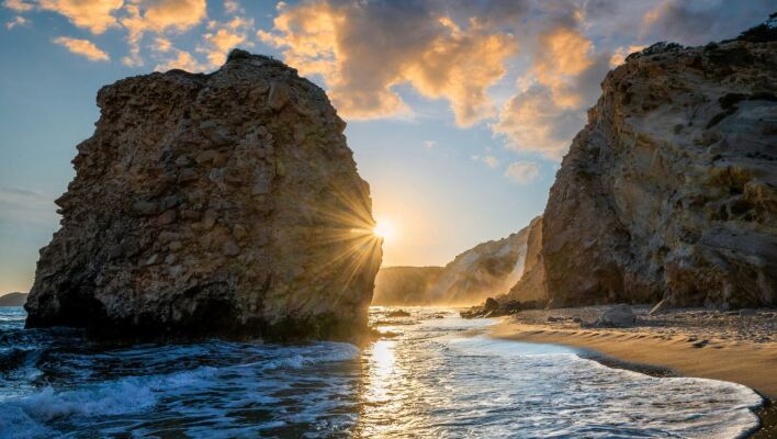 Ηλιοβασίλεμα ανάμεσα σε δύο βράχους σε παραλία της Μήλου