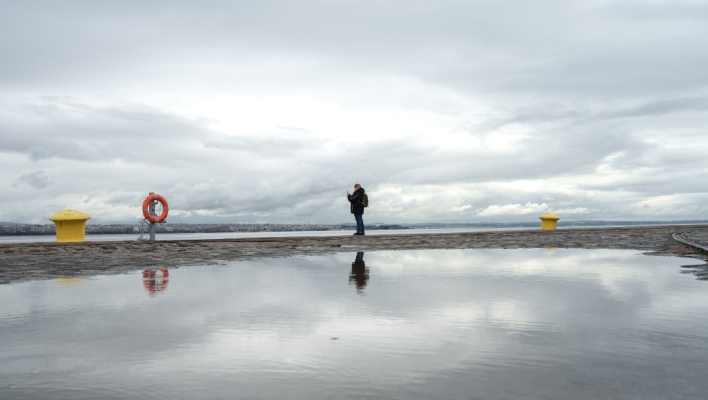 Γυναίκα στέκεται στην παραλία της Θεσσαλονίκης με συννεφιασμένο καιρό