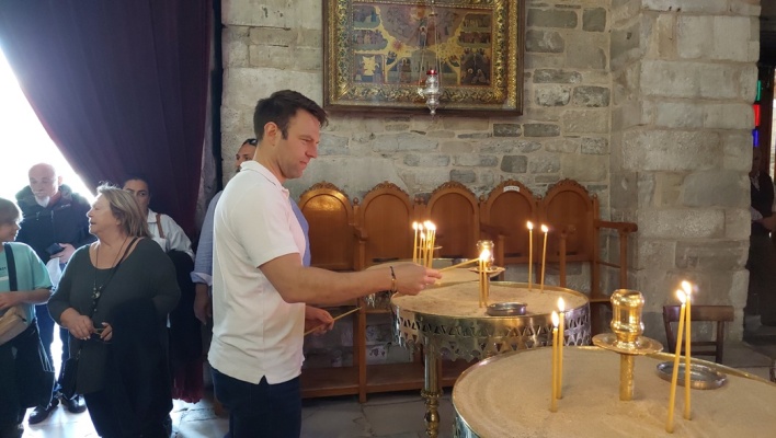 Ο Στέφανος Κασσελάκης ανάβει κεράκι σε εκκλησία κατά τη διάρκεια της περιοδείας του στα νησιά