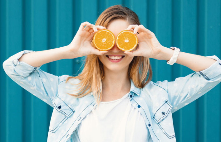 Κορίτσι που κρατάει ροδέλες πορτοκαλιού μπροστά στα μάτια της