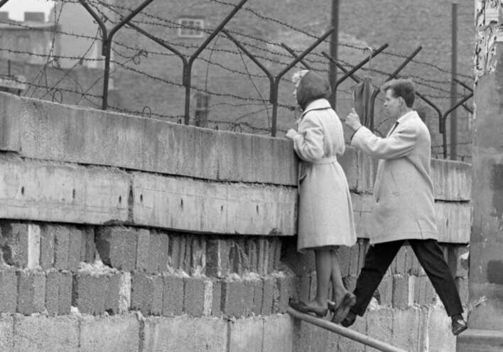 21 Απριλίου, 1962 | Μια νεαρή γυναίκα, συνοδευόμενη από τον φίλο της, στέκεται στην κορυφή του Τείχους του Βερολίνου για να μιλήσει με τη μητέρα της στην πλευρά του Ανατολικού Βερολίνου