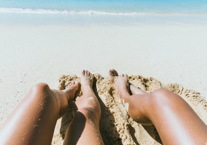 Γυναικεία πόδια στην άμμο παραλίας