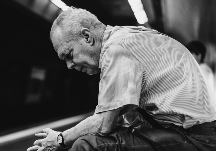 Ασπρόμαυρη φωτογραφία καθιστού ηλικιωμένου άνδρα σε σταθμό μετρό