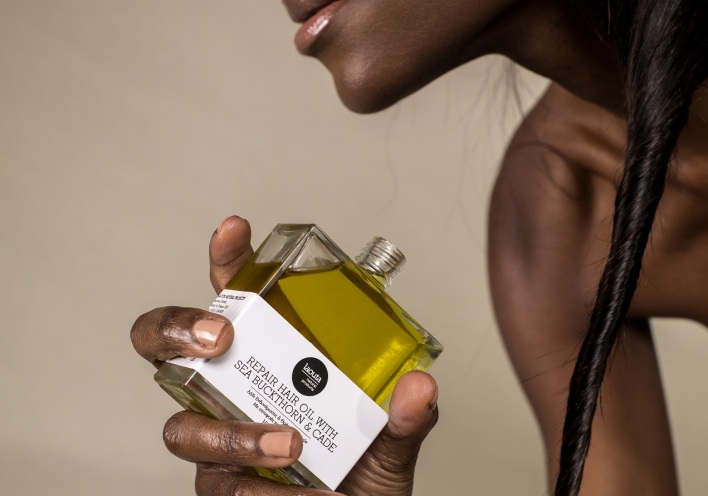 Μαύρη γυναίκα κρατάει μπουκαλάκι με έλαιο Laouta