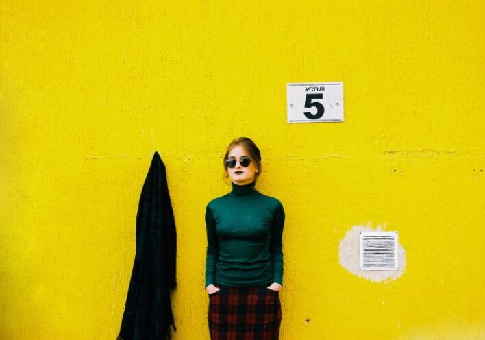 Γυναίκα που φορά γυαλιά ηλίου με φόντο κίτρινο τοίχο