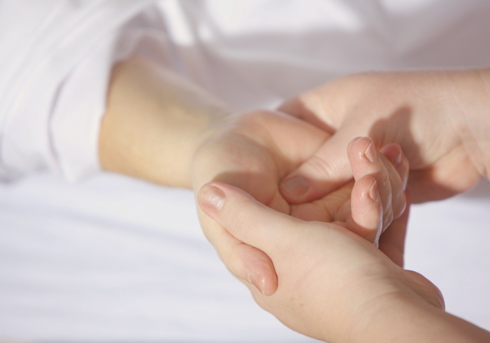 Εικόνα με μία γιατρό να εξετάζει ένα χέρι.