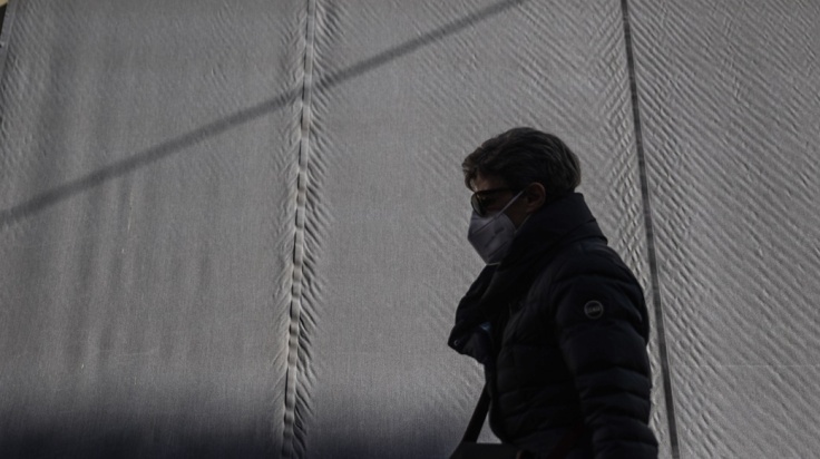 Γυναίκα περπατά φορώντας τη μάσκα προστασίας κατά του κορωνοϊού