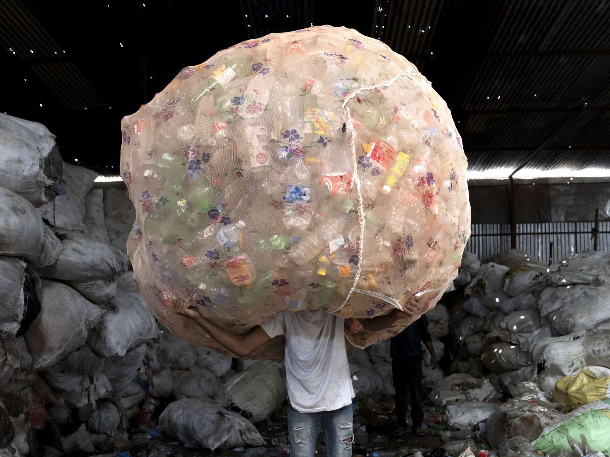 Ένας εργαζόμενος μεταφέρει δέσμες με μπουκάλια PET (τερεφθαλικό πολυαιθυλένιο) 