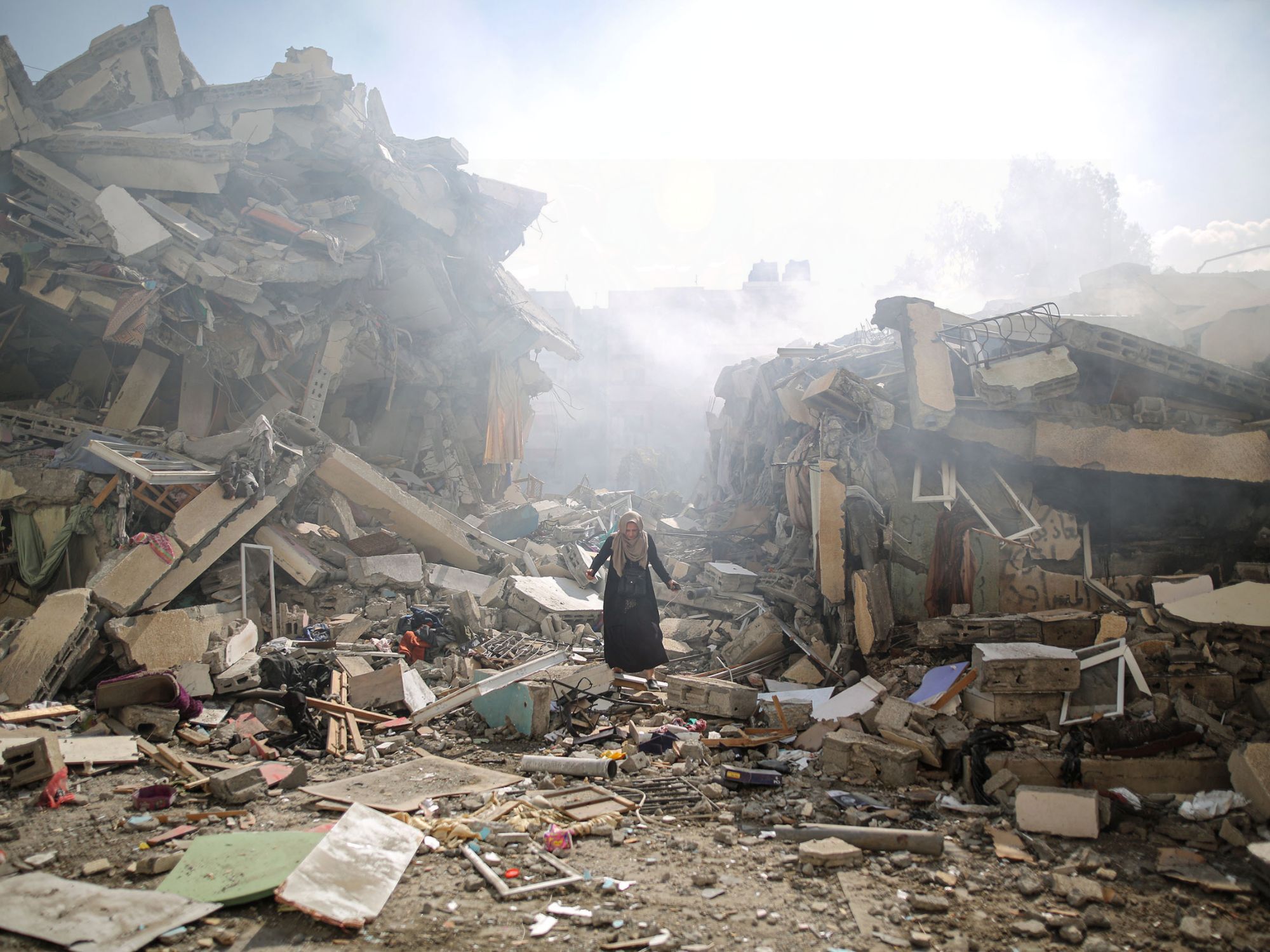 Γυναίκα περπατά ανάμεσα στα ερείπια κτιρίων και κατοικιών μετά τις ισραηλινές αεροπορικές επιδρομές στη Γάζα