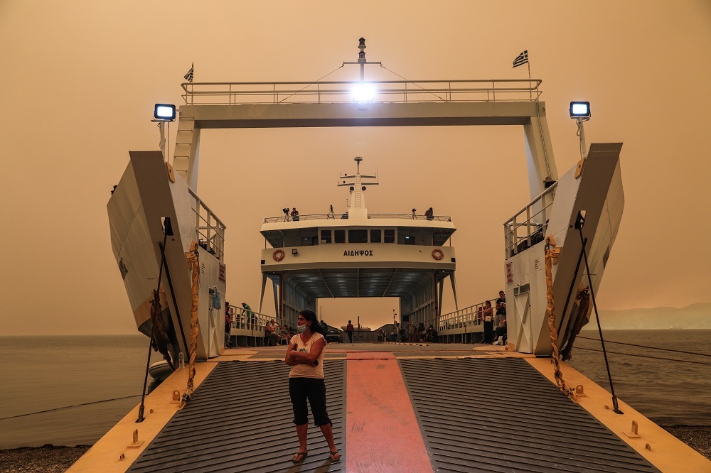 Κάτοικος κοιτάει το νησί της Εύβοιας, λίγο πριν αναχωρήσει με το φέρι μποτ, μετά από εντολή εκκένωσης. 