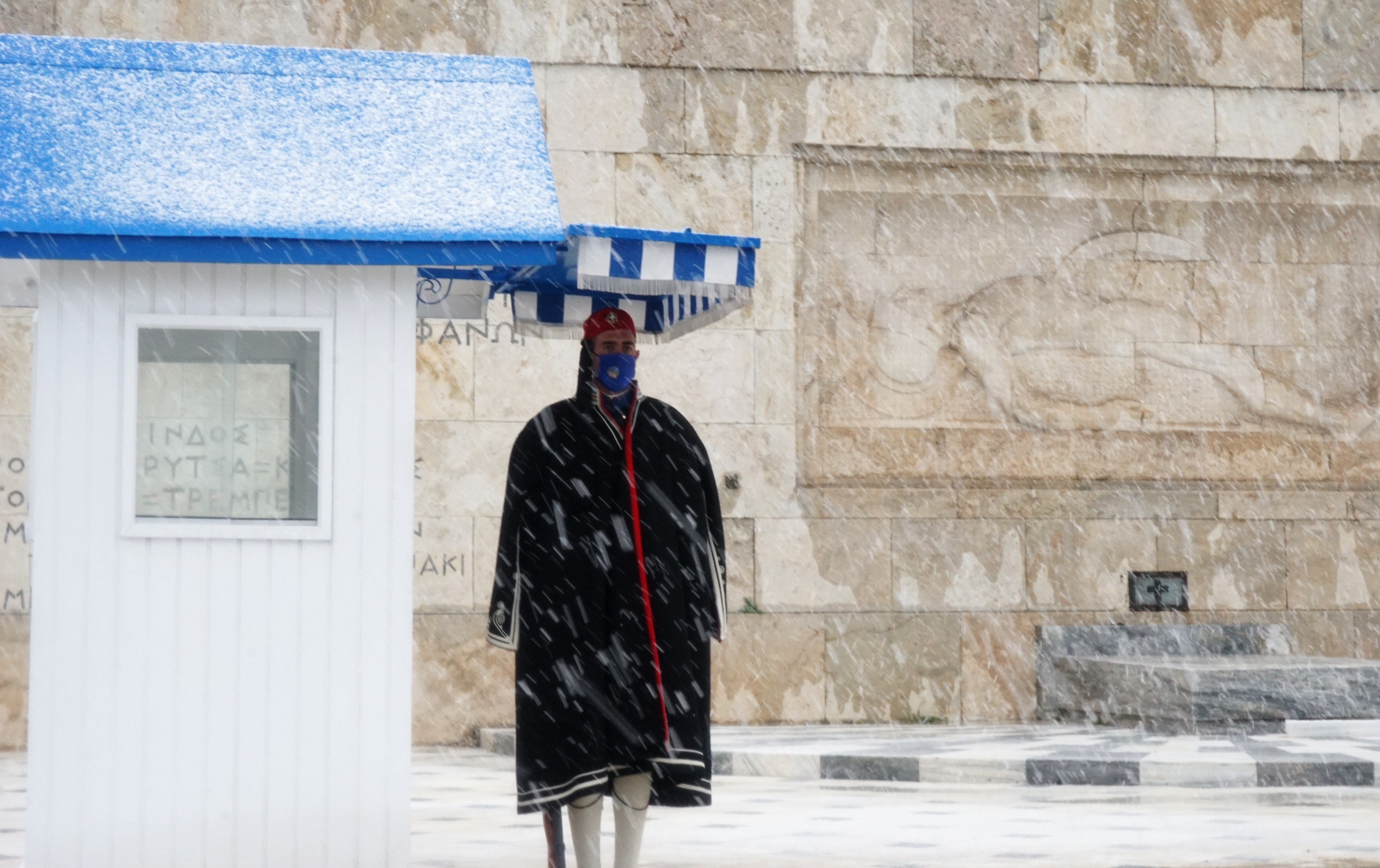 Οι Εύζωνες στέκονται στο Μνημείο του Άγνωστου Στρατιώτη παρά τις αντίξοες καιρικές συνθήκες.
