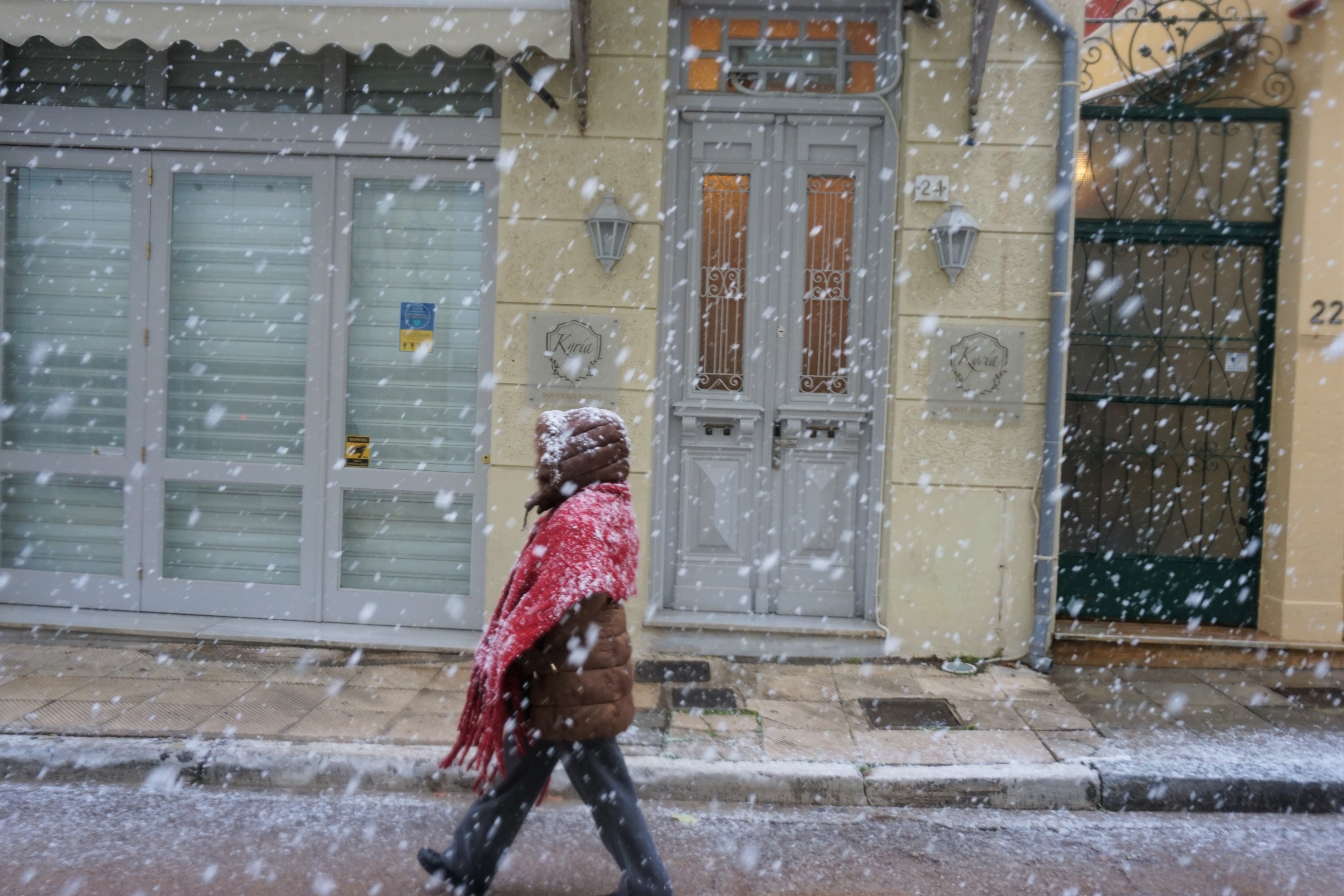 Μια γυναίκα περπατάει την ώρα που έχει ξεκινήσει μεγάλη χιονόπτωση στο κέντρο της Αθήνας. 