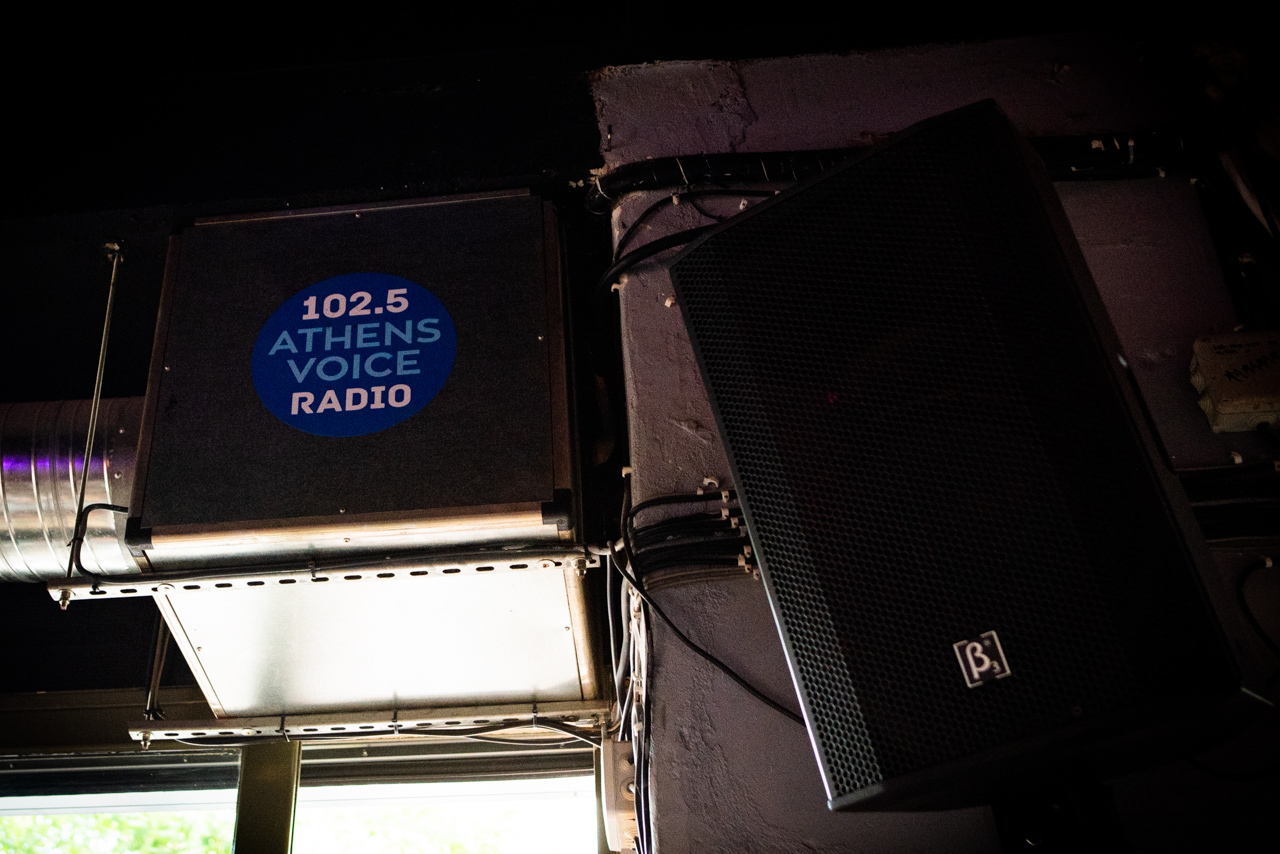 Το σήμα του ραδιοφωνικού σταθμού Athens Voice 102.5 στο μπαρ Εφημερίδα ATH
