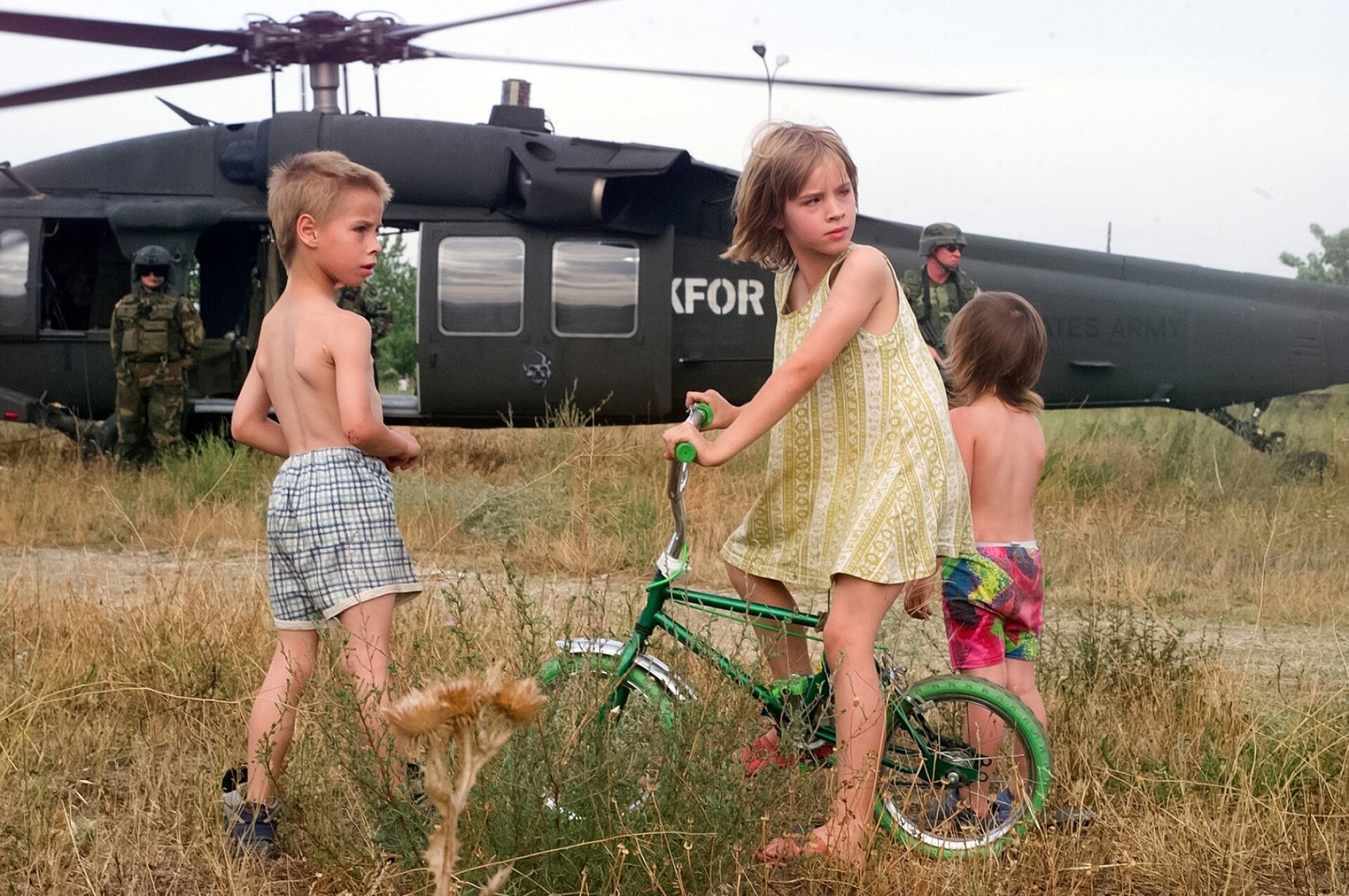 Νίκος Γιακουμίδης, Παιδιά χαζεύουν ελικόπτερο του ΝΑΤΟ, Σκόπια, Ιούνιος 2003 Έκθεση Νίκος Γιακουμίδης (1963-2022): μια μικρή αναδρομή στο έργο του  Αρχαιολογικό Μουσείο Θεσσαλονίκης / 12.10-30.11.2023   