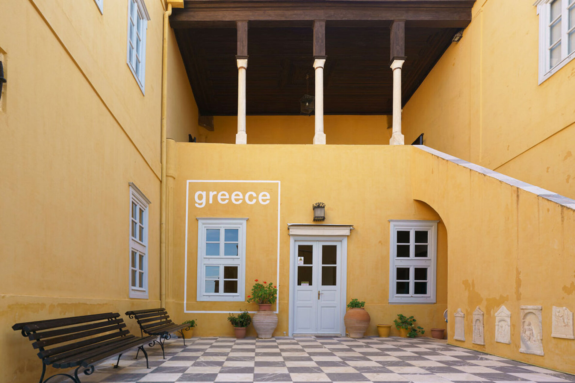 Κεντρική αυλή της Ιστορικής Οικίας Λαζάρου Κουντουριώτη με την τοιχογραφία που μετατρέπει παράθυρο της κεντρικής αυλής της Ιστορικής Οικίας Λαζάρου Κουντουριώτη σε τουριστική αφίσα