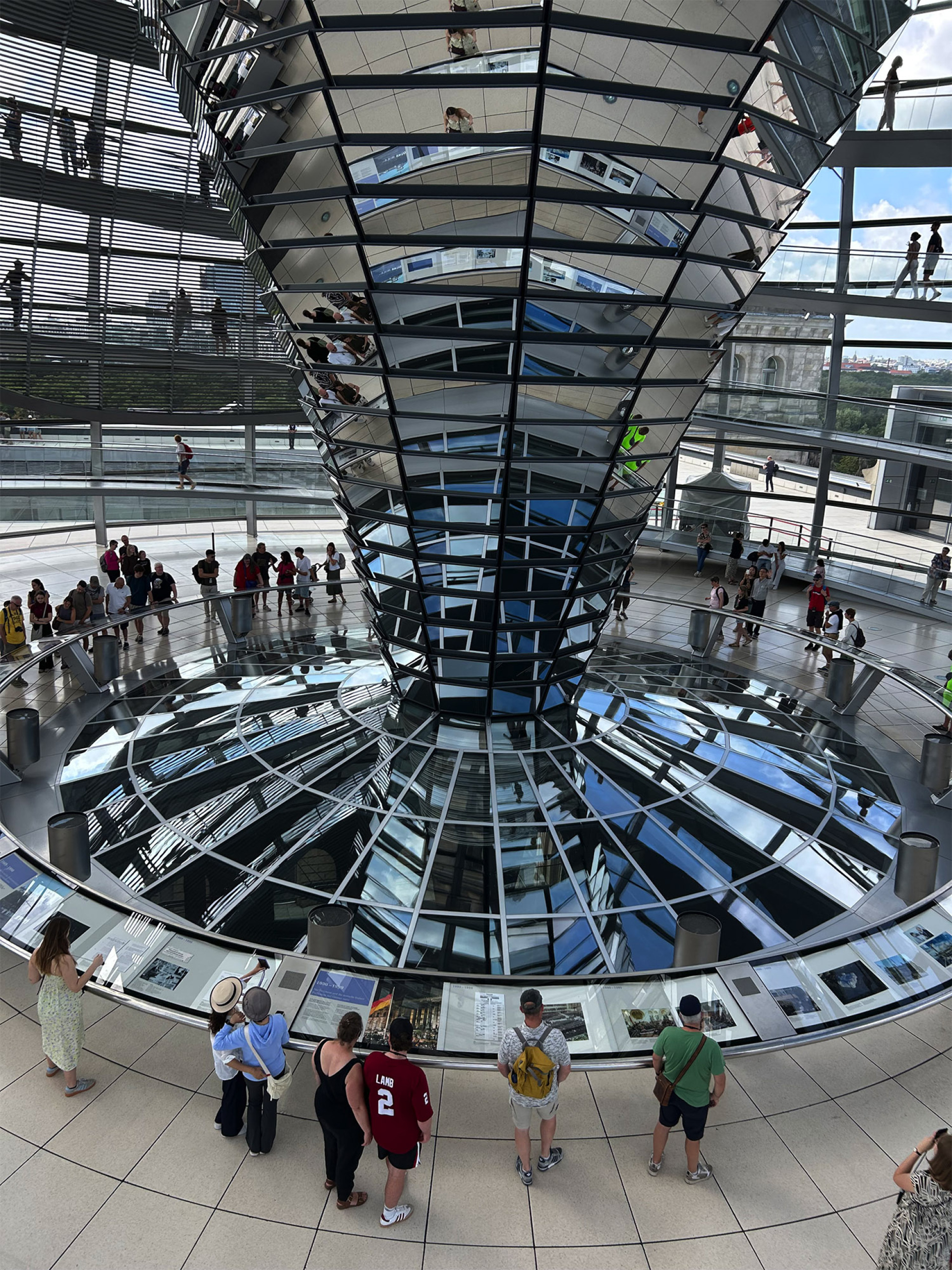 Το εσωτερικό του γυάλινου θόλου του Ράιχσταγκ, με τον κώνο από καθρέφτες που φωτίζει φυσικά την αίθουσα της Ολομέλειας και αφηγείται την ιστορία του κτιρίου