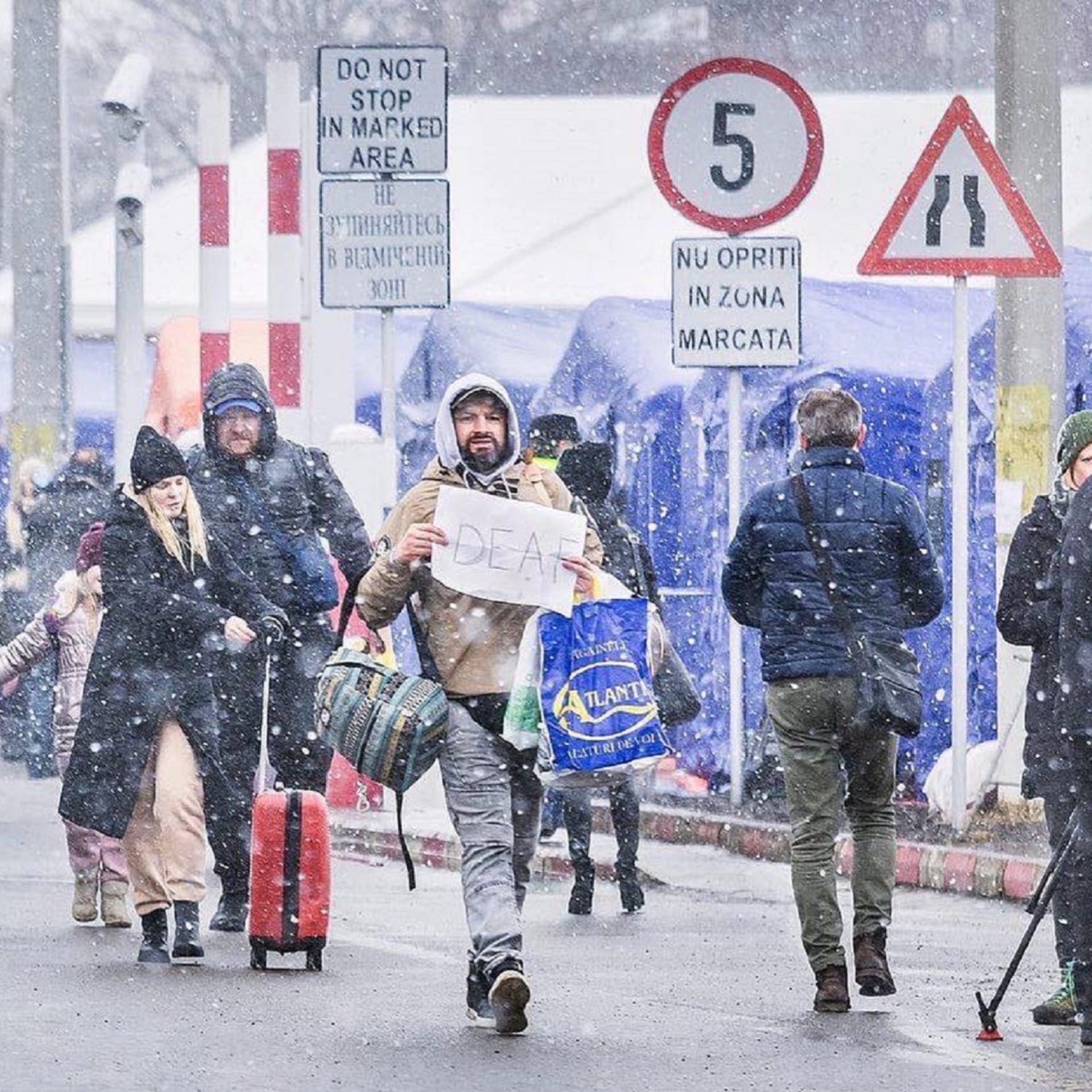 Ουκρανοί πρόσφυγες καταφθάνουν στα σύνορα στο Σιρέτ. Διακρίνεται ένας άνδρας να κρατάει ένα πλακάτ που γράφει «κωφός».