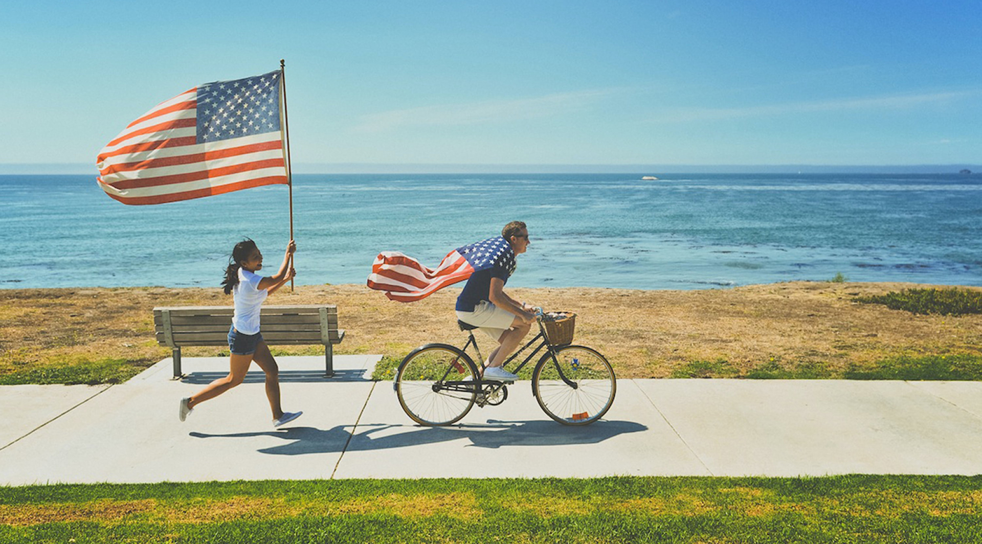 Ένας άντρας με ποδήλατο και μια γυναίκα πεζή με σημαίες της Αμερικής