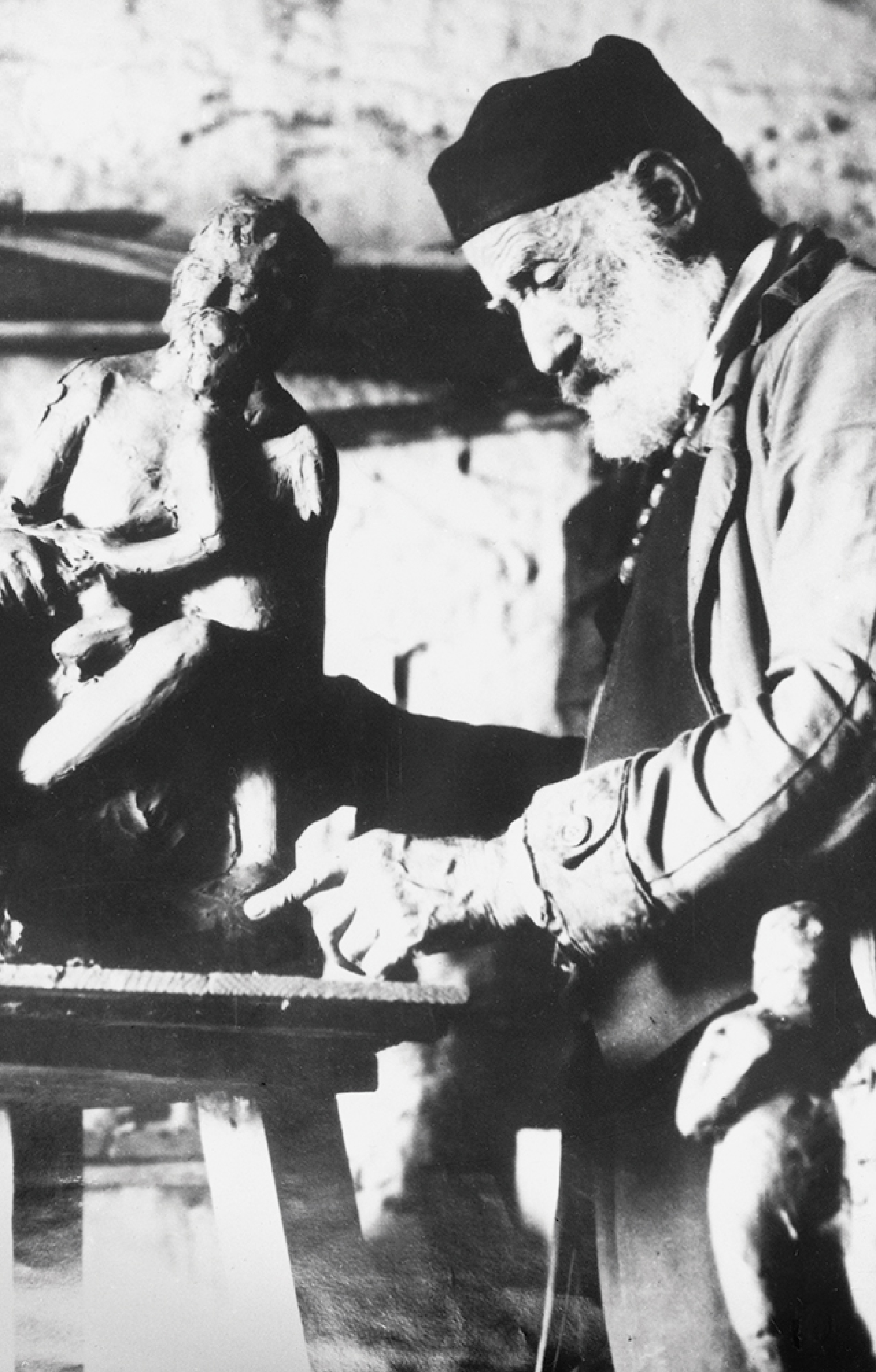 Ο Γιανούλης Χαλεπάς και πίσω του το έργο «Σάτυρος και Έρως Χ», του 1931, με τον Σάτυρο να γέρνει τρυφερά προς την παιδική μορφή που κάθεται στον αριστερό του μηρό και ακουμπάει άνθη δίπλα στο χέρι του, στο οποίο κρατάει σύριγγα. 