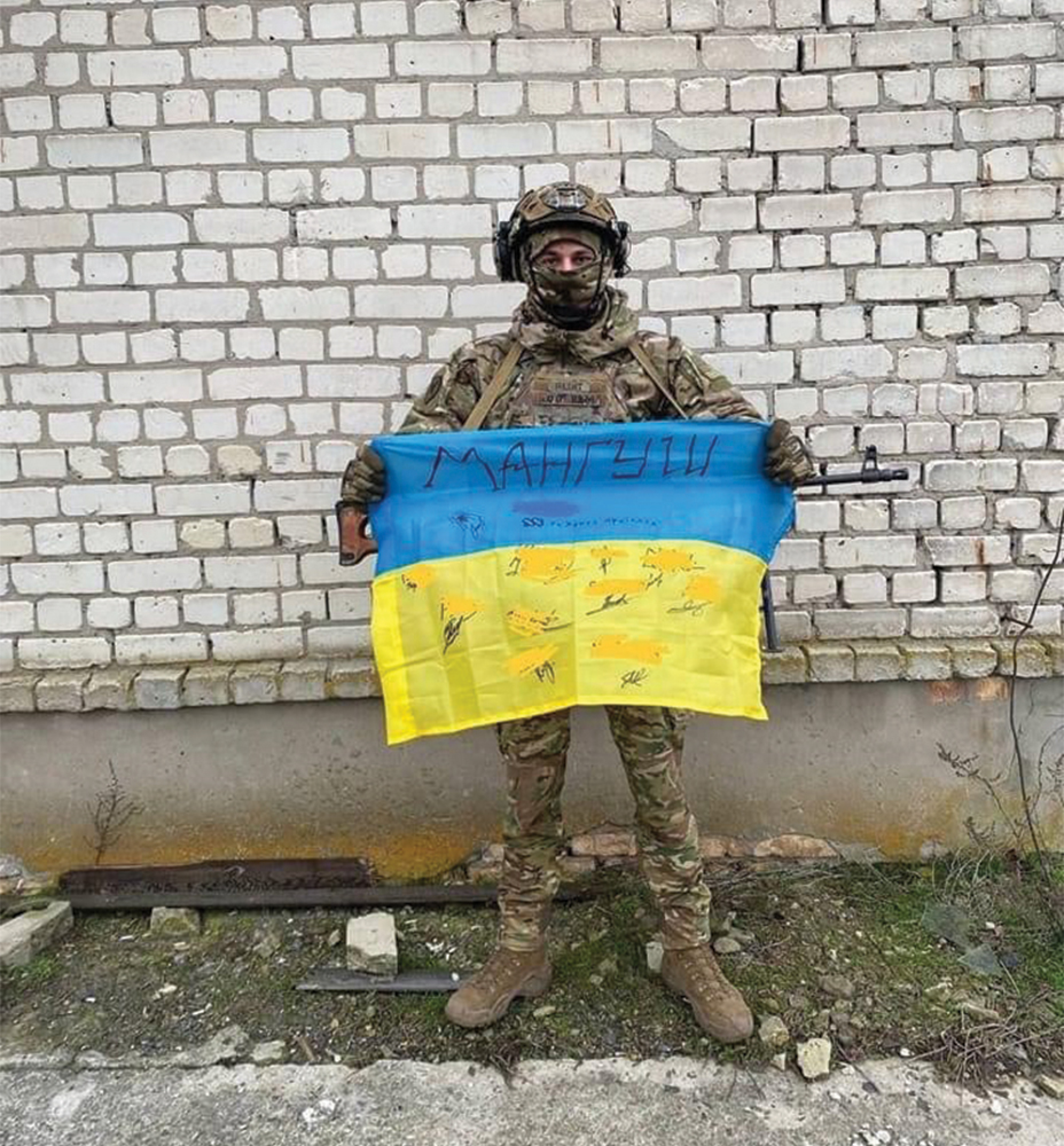 Έλληνας μαχητής της Μαριούπολης κρατάει τη σημαία της Ουκρανίας.