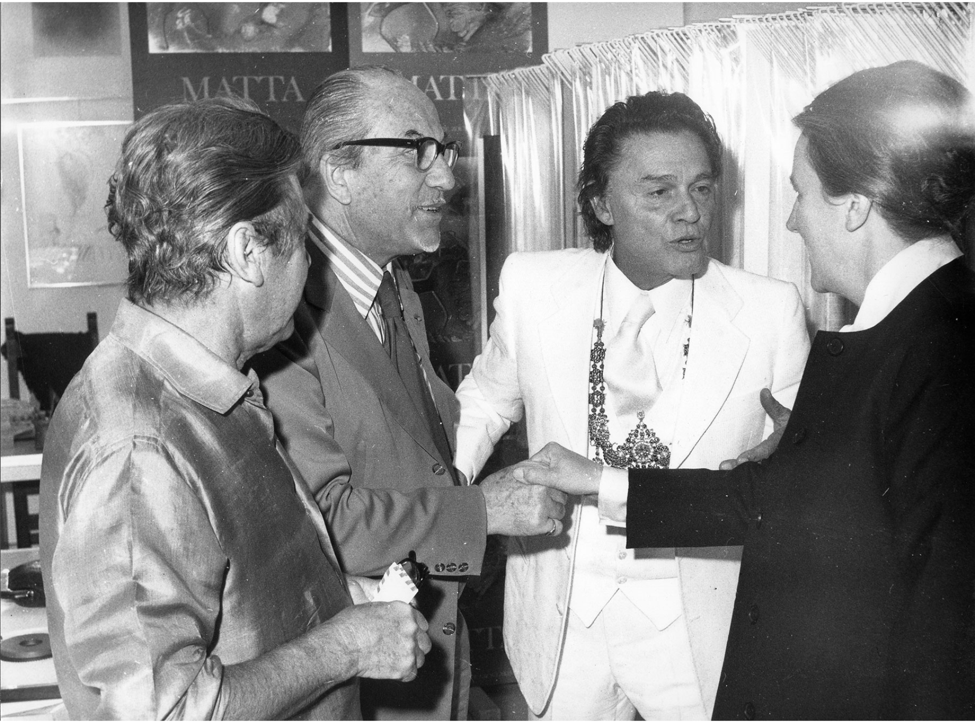 1 Μαρτίου 1975. Ομαδική έκθεση των Man Ray, Max Ernst, Matta, Pavlos, Takis, Νικολάου, Γκίκα, Μόραλη. Από τα εγκαίνια της έκθεσης βλέπουμε τον Ιόλα να συστήνει το σπουδαίο Χιλιανό ζωγράφο Roberto Matta στο κοινό.